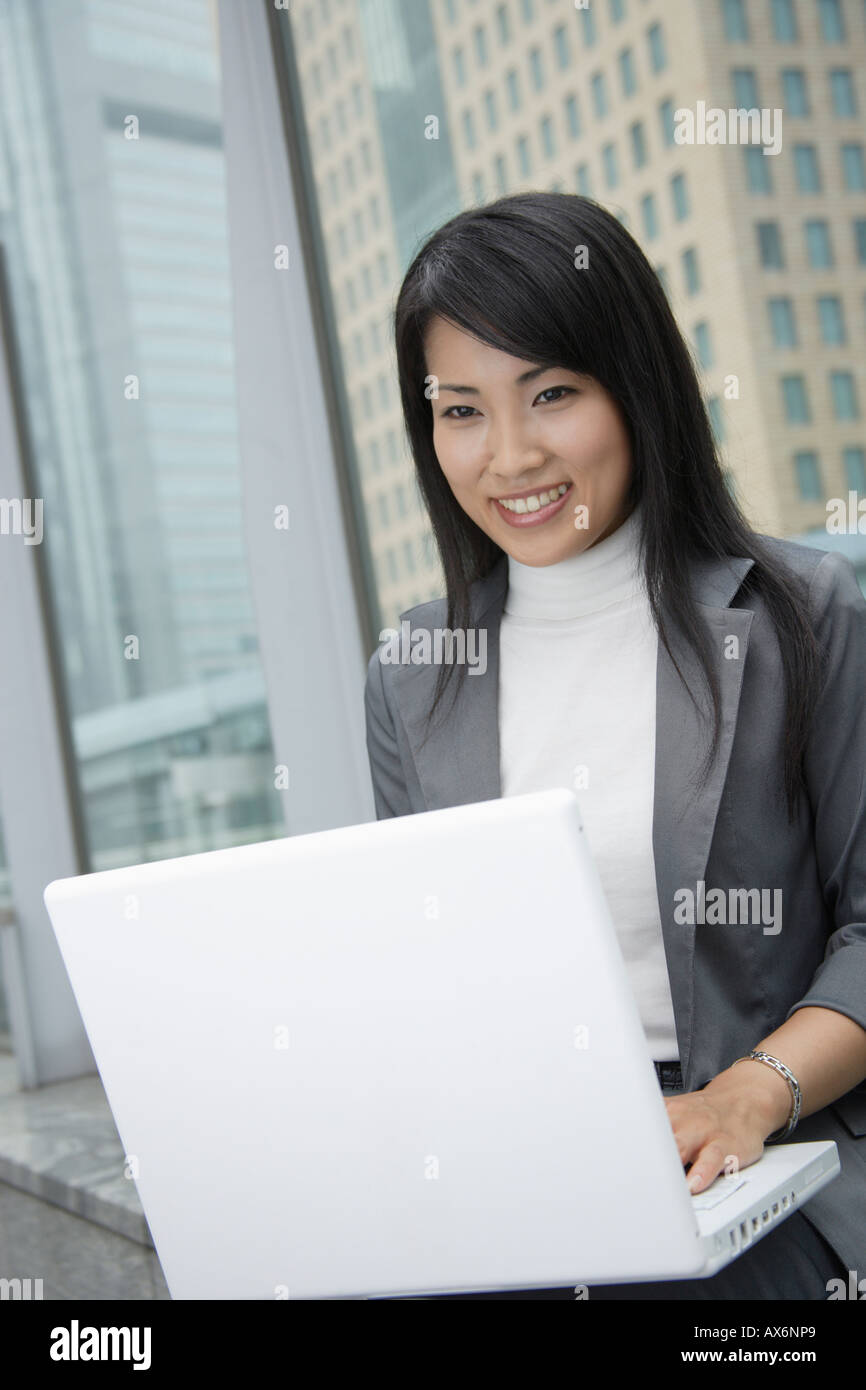 A woman working over her laptop as she smiles at the camera Stock Photo ...