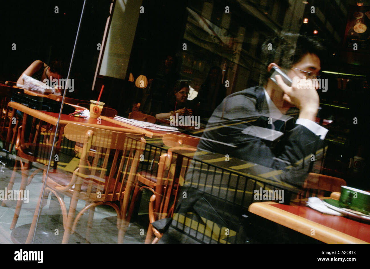 Man on mobile phone in Hong Kong sits inside the popular Pacific Coffee