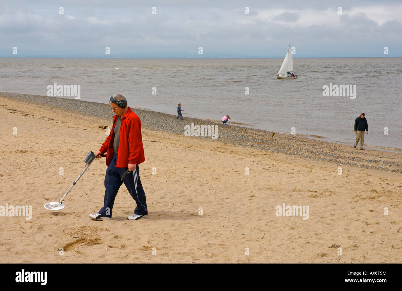 Man with metal detector, treasure hunting on the beach at Fleetwood, Lancashire, England UK