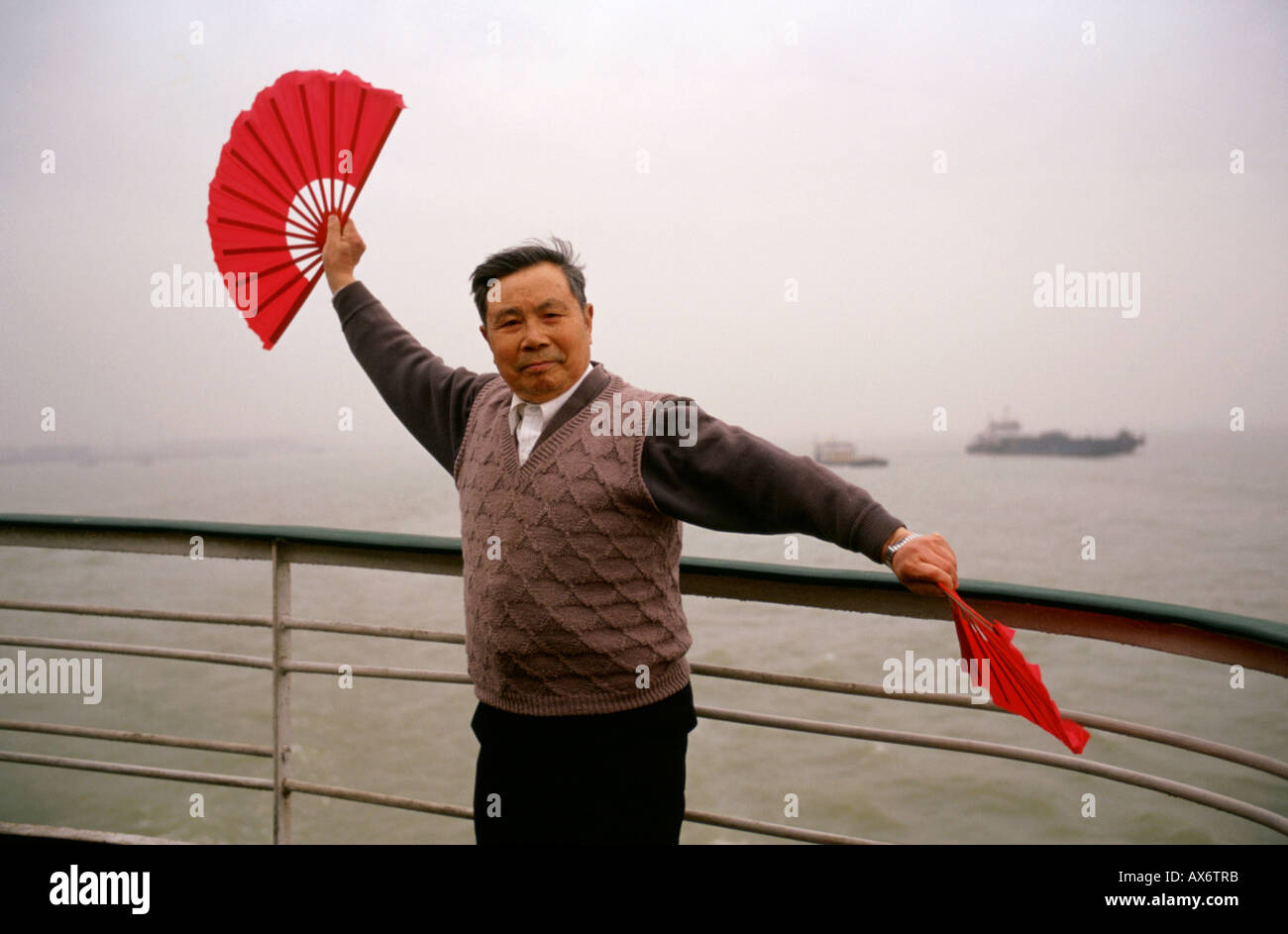 A Chinese man fan dances on the back side of a boat going down the Yangtze River Stock Photo