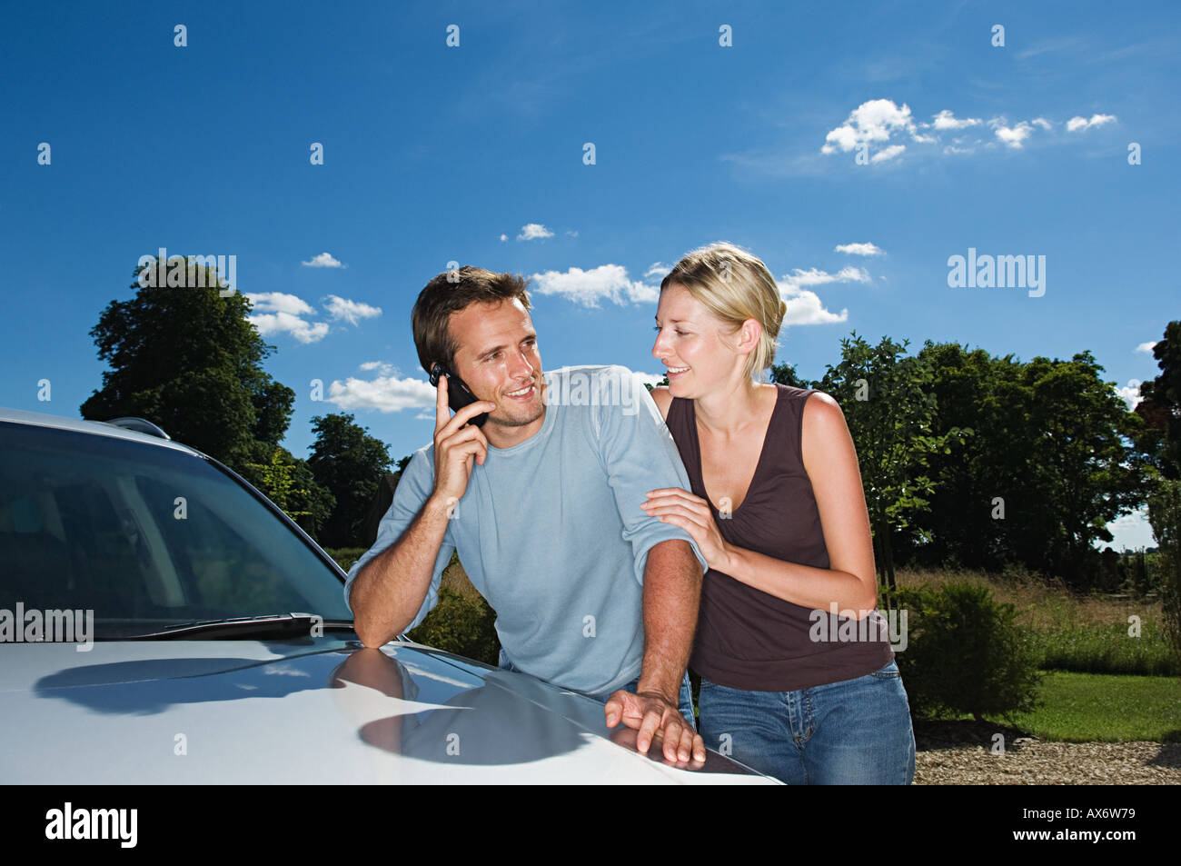Couple by car using mobile phone Stock Photo