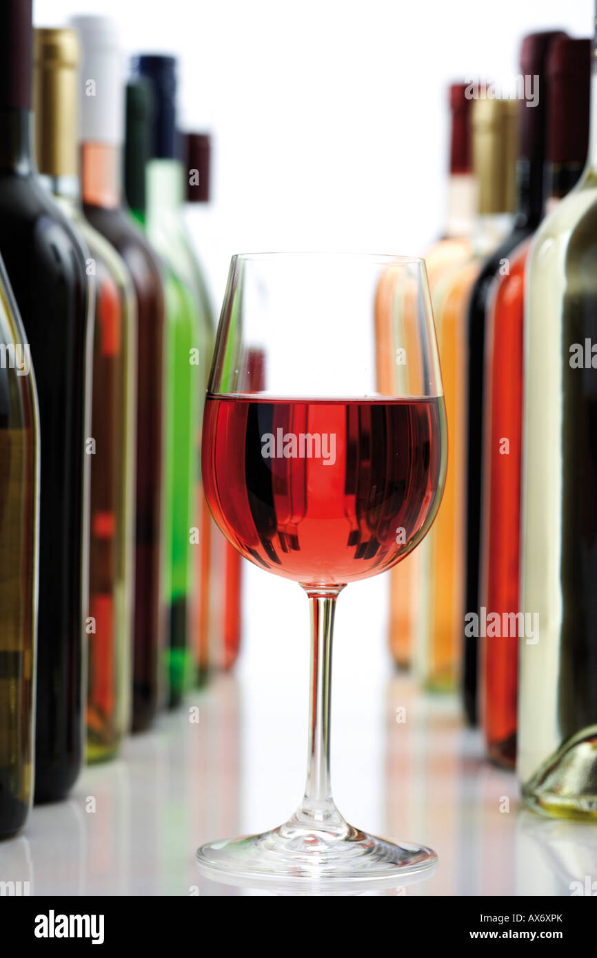 Glass of red wine between wine bottles, close-up Stock Photo