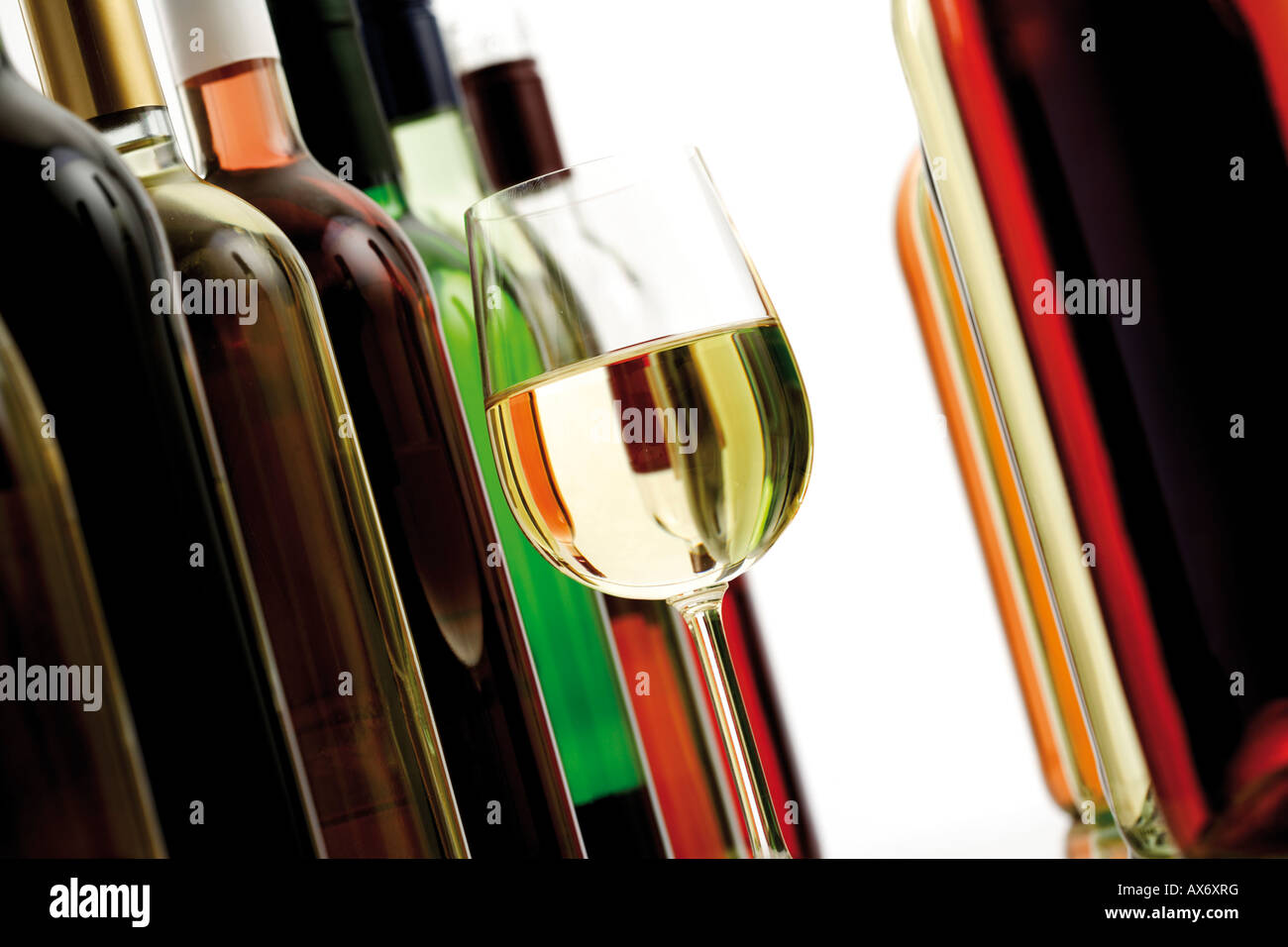 Glass of white wine between wine bottles, close-up Stock Photo