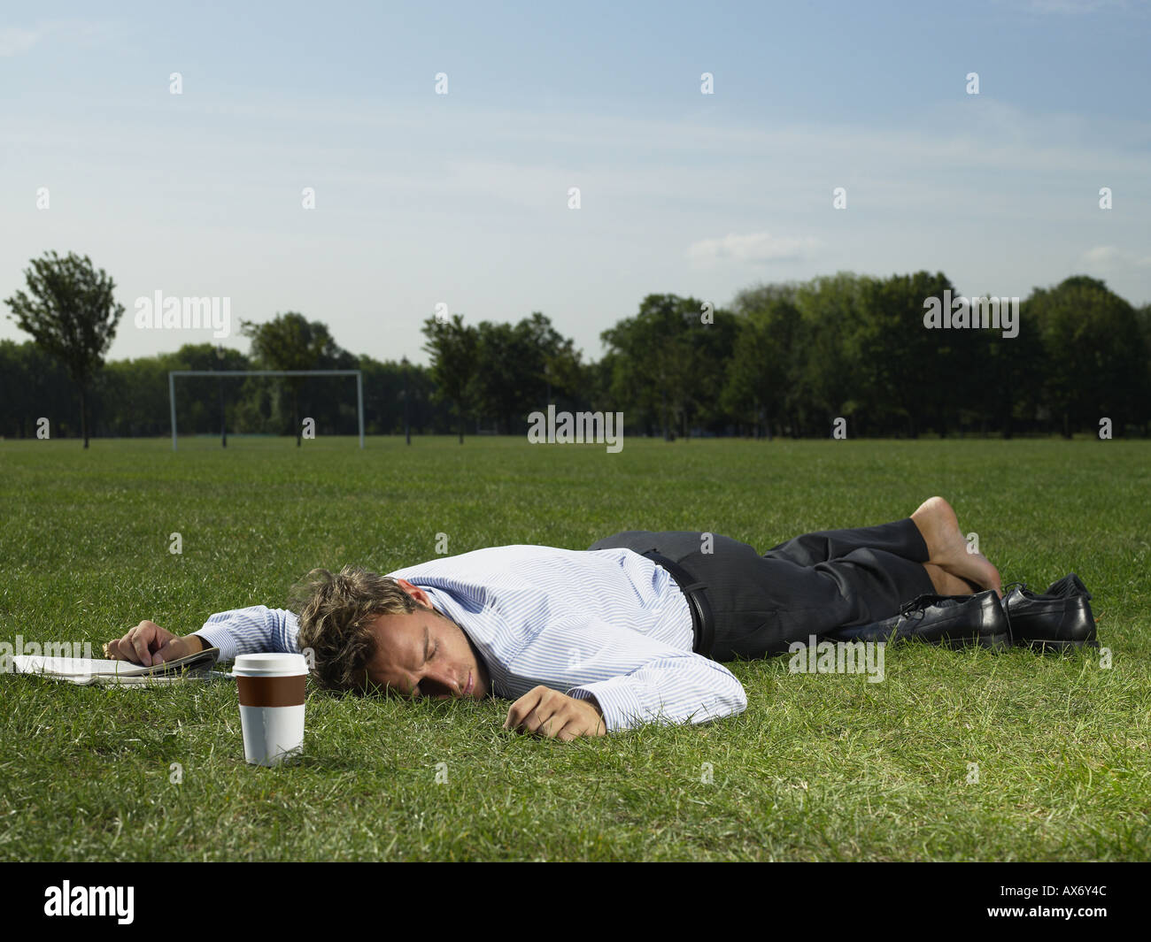 Male office worker sleeping in a park Stock Photo