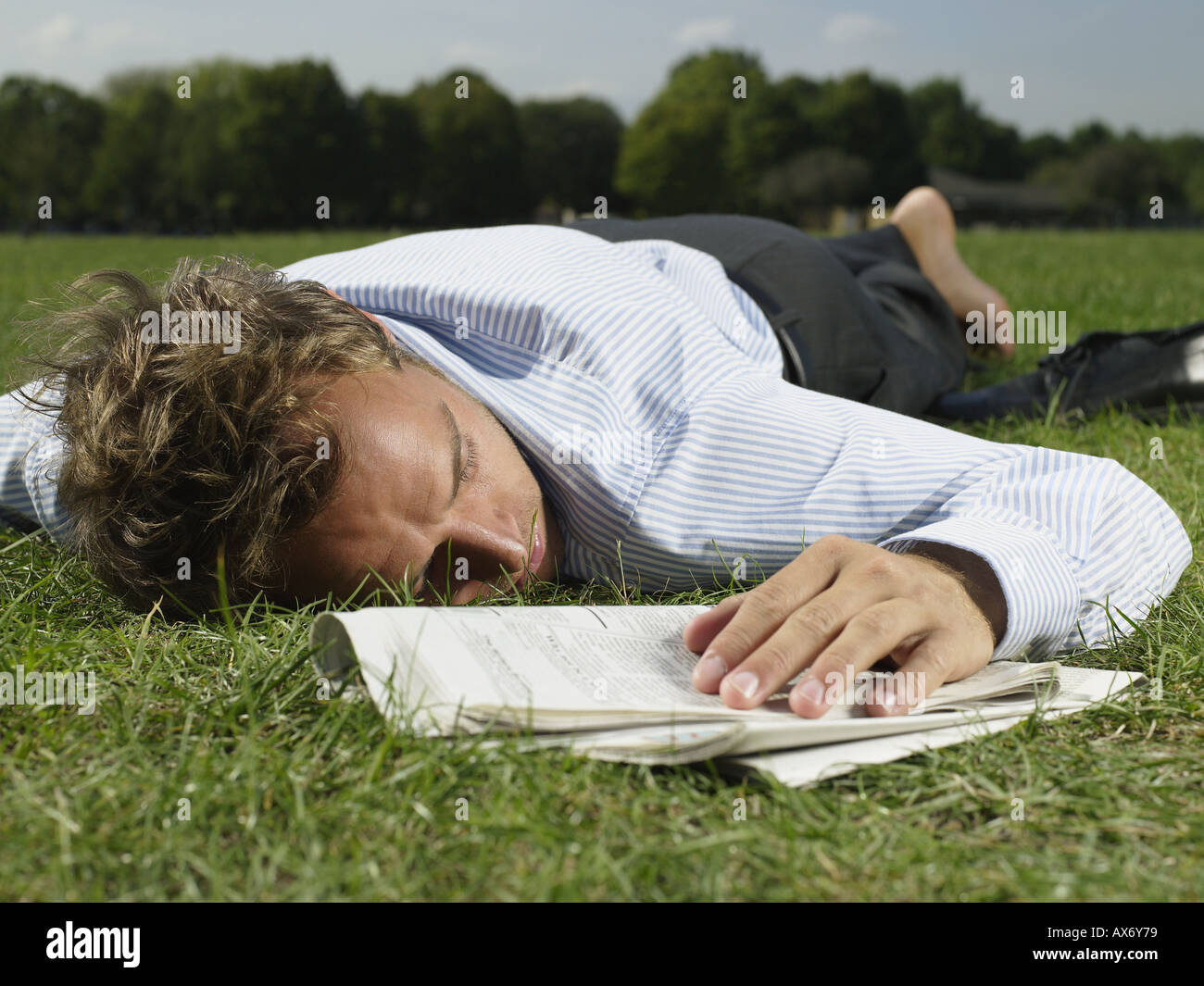 Male office worker sleeping in a park Stock Photo