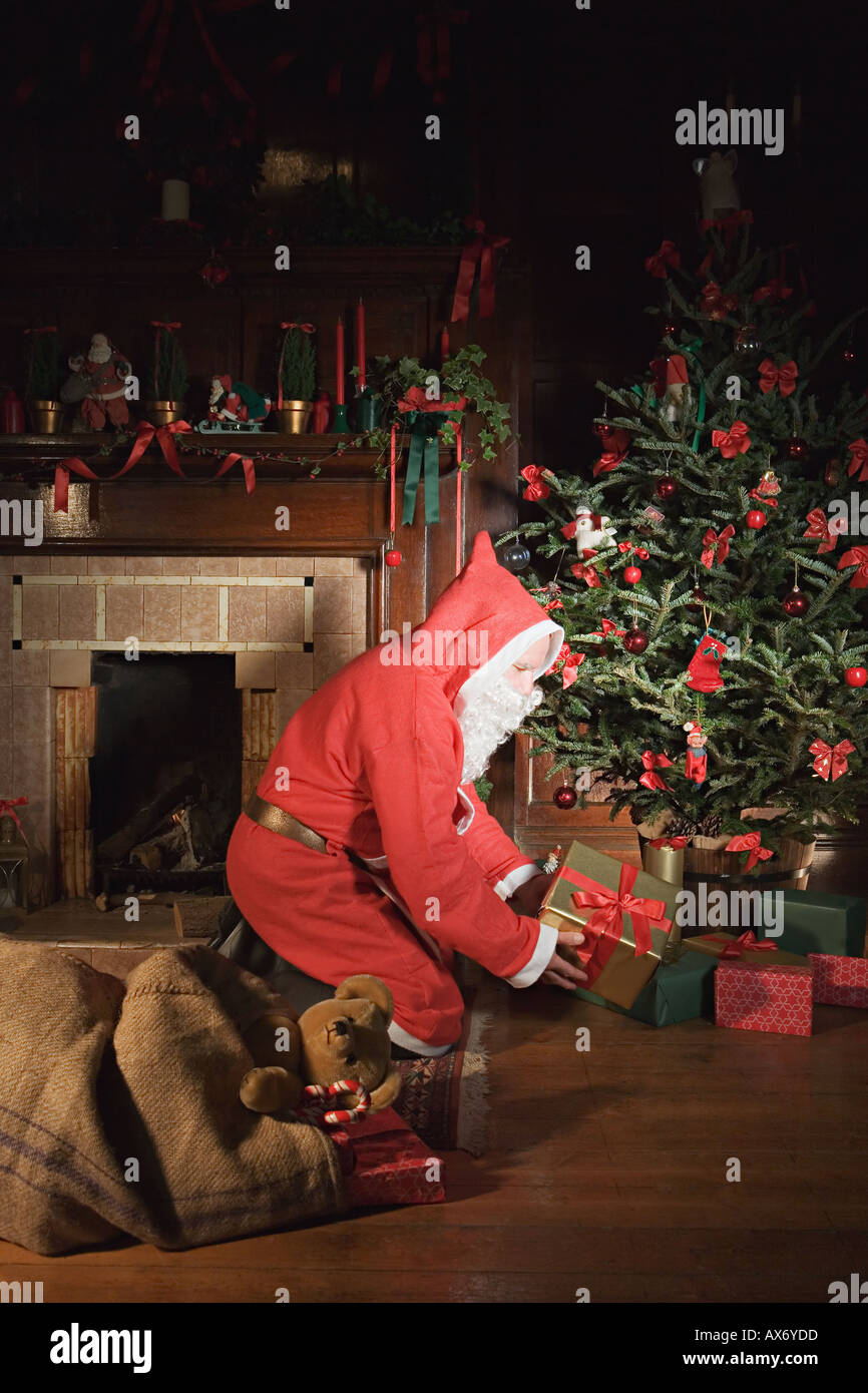 Santa claus placing presents under christmas tree Stock Photo