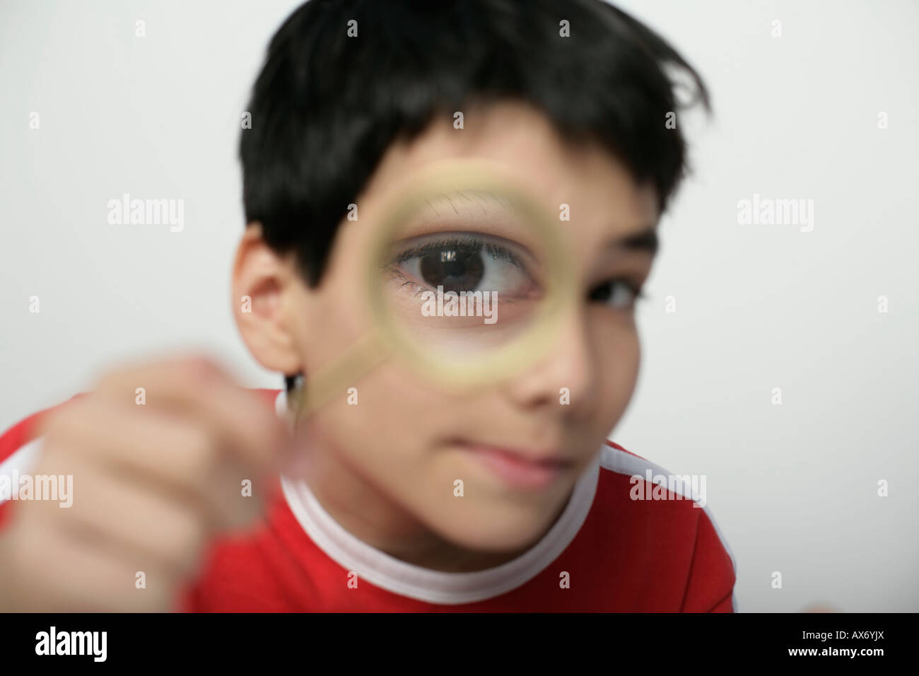 Boy looking through a magnifying glass at camera, fully released Stock Photo