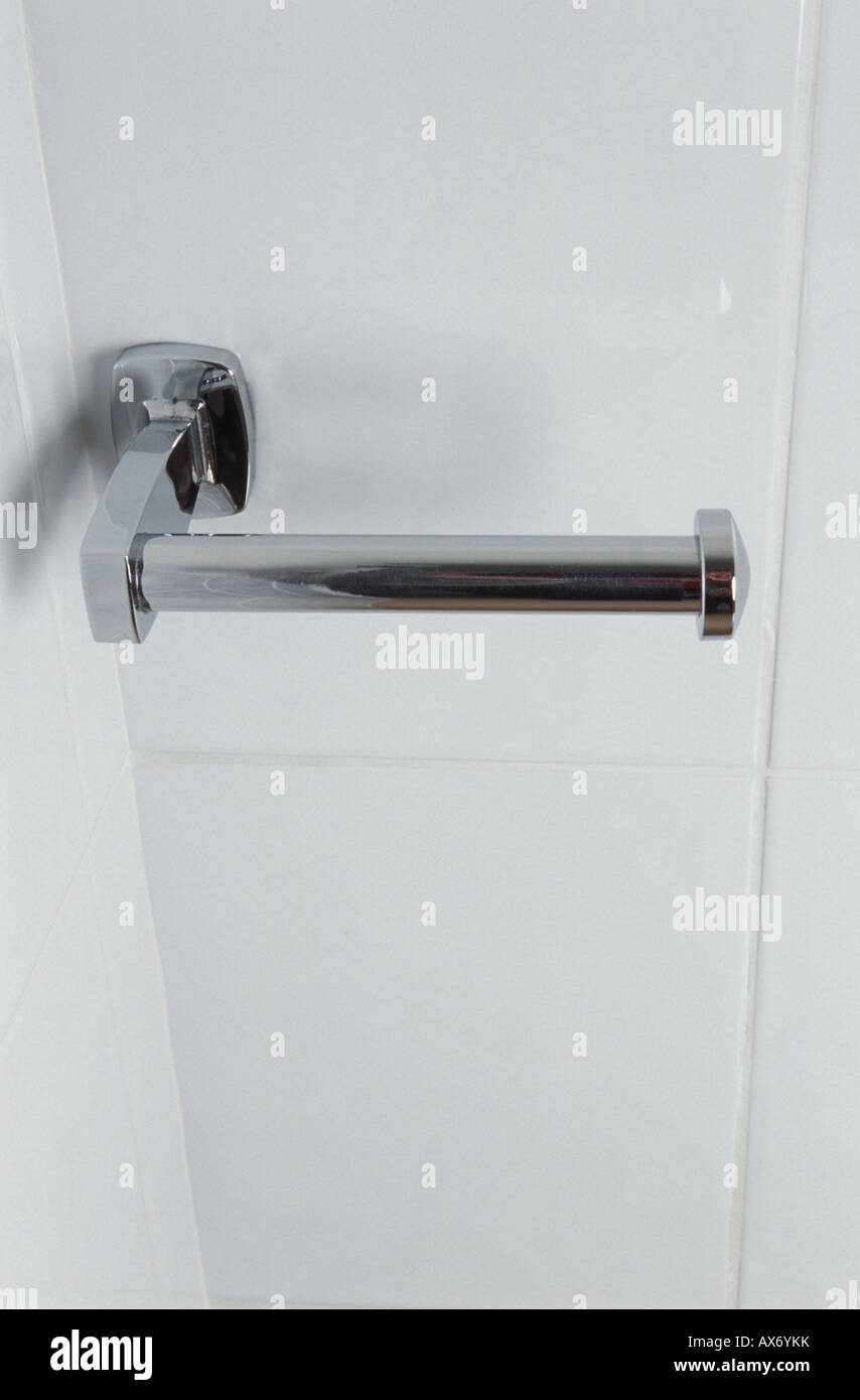 Chrome toilet roll holder mounted on white ceramic tiles Stock Photo