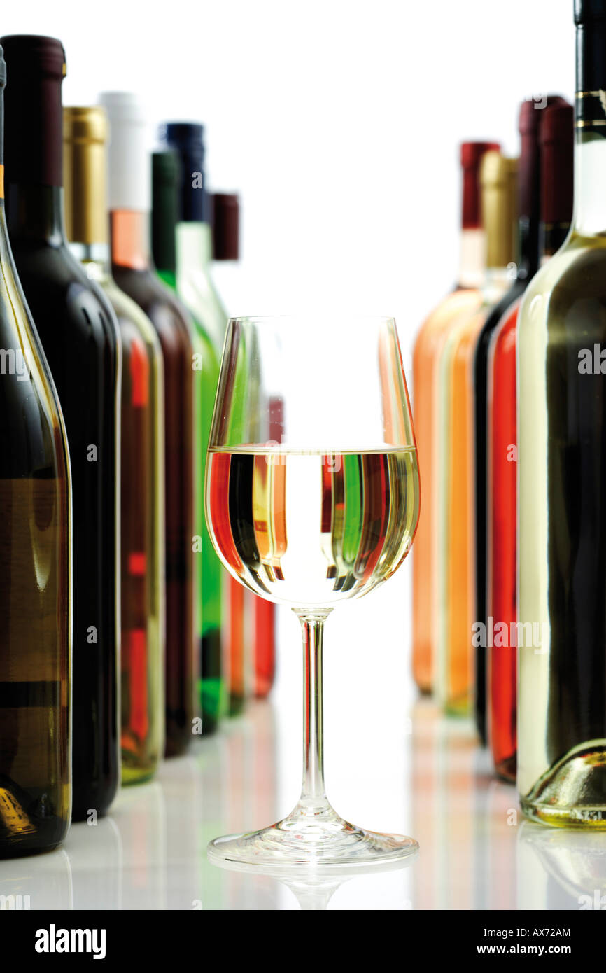 Glass of white wine between wine bottles, close-up Stock Photo
