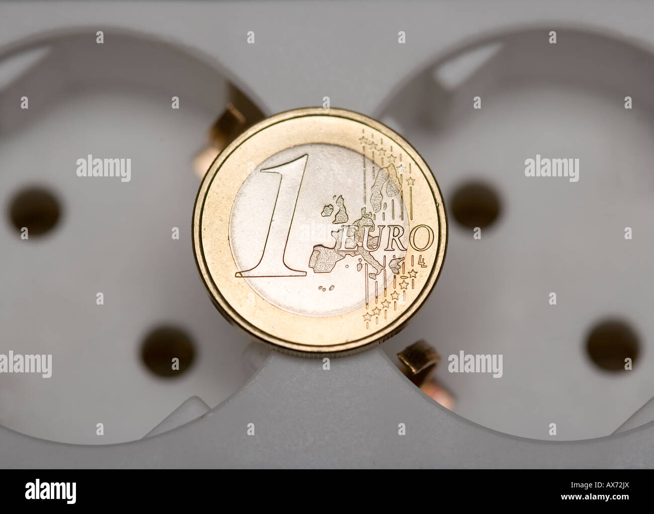 1 Euro coin lying on multyplug connector Symbol energy costs power price etc Stock Photo