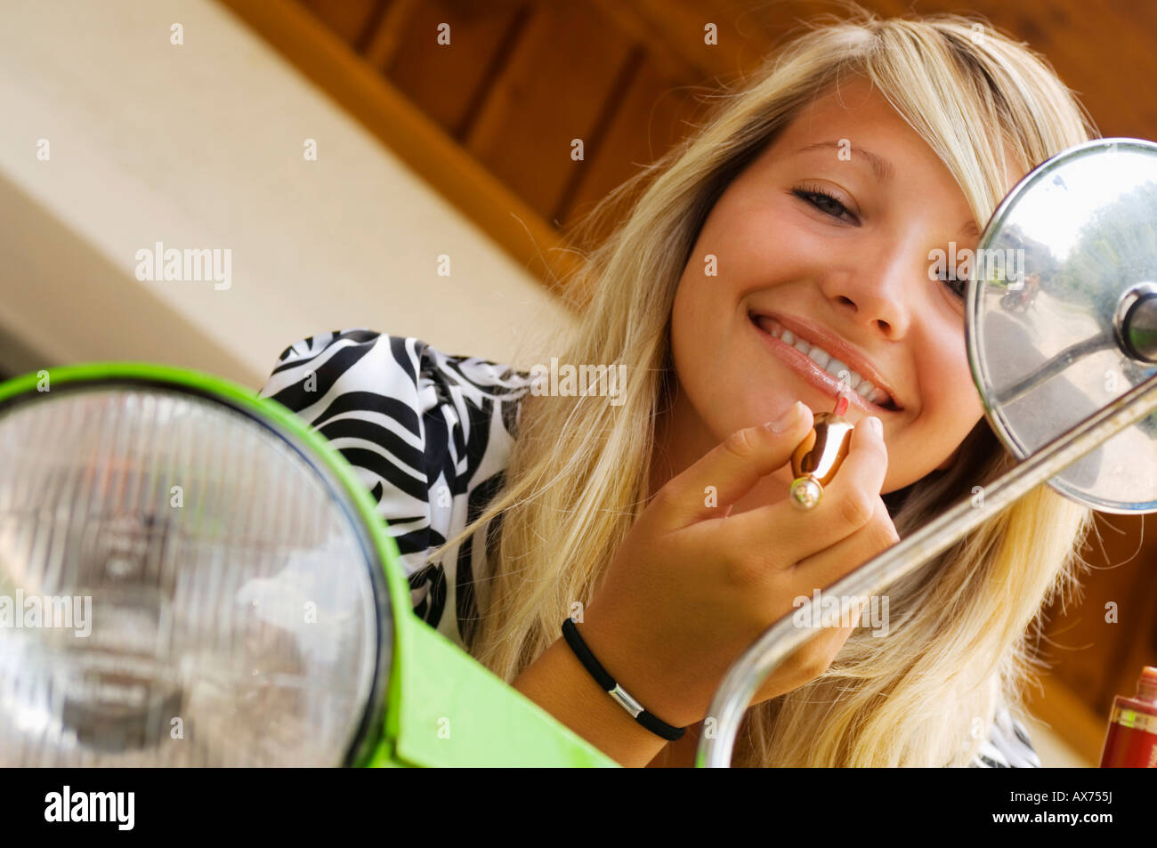 Young woman applying lipstick, smiling Stock Photo