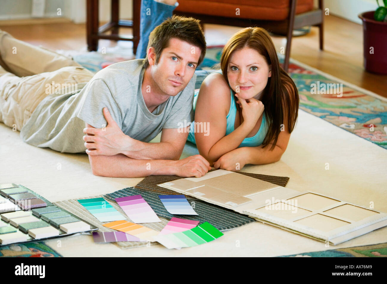 Portrait of a young couple lying down with color swatches in front of ...