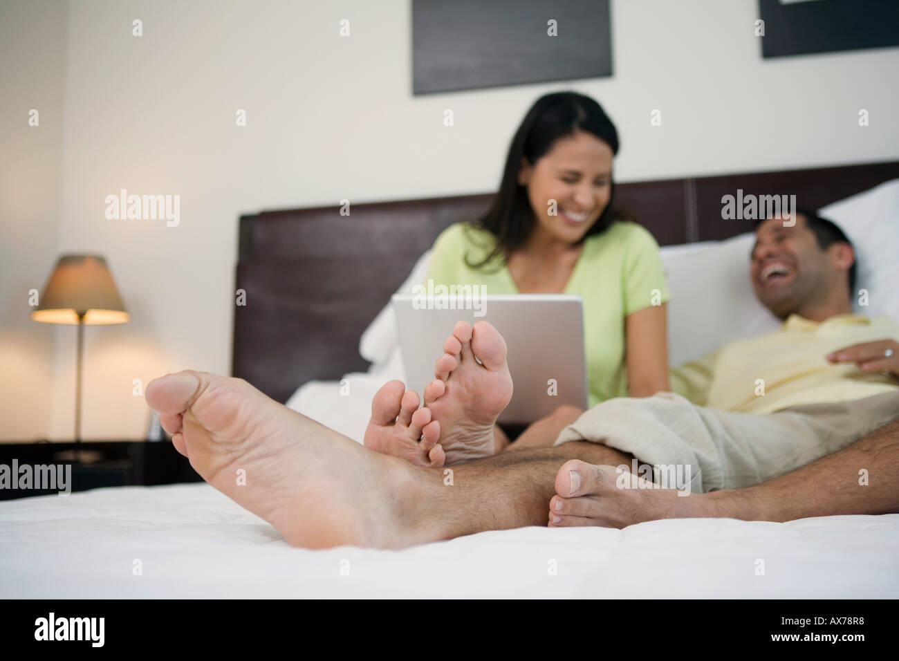 Mature man lying in the bed with a mature woman sitting beside him with ...