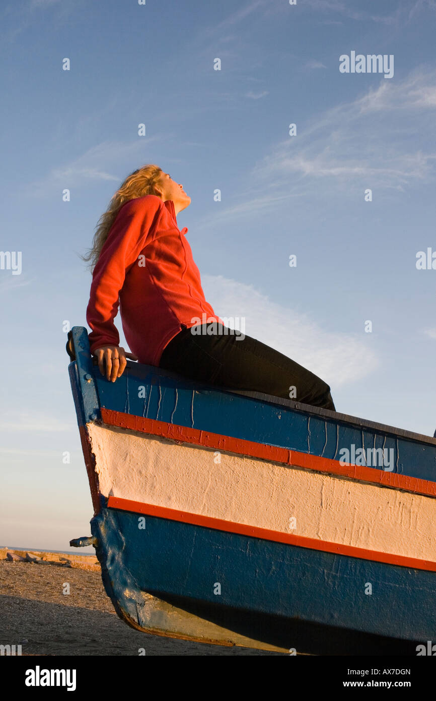 Young woman sitting in boat looking up at sky Stock Photo