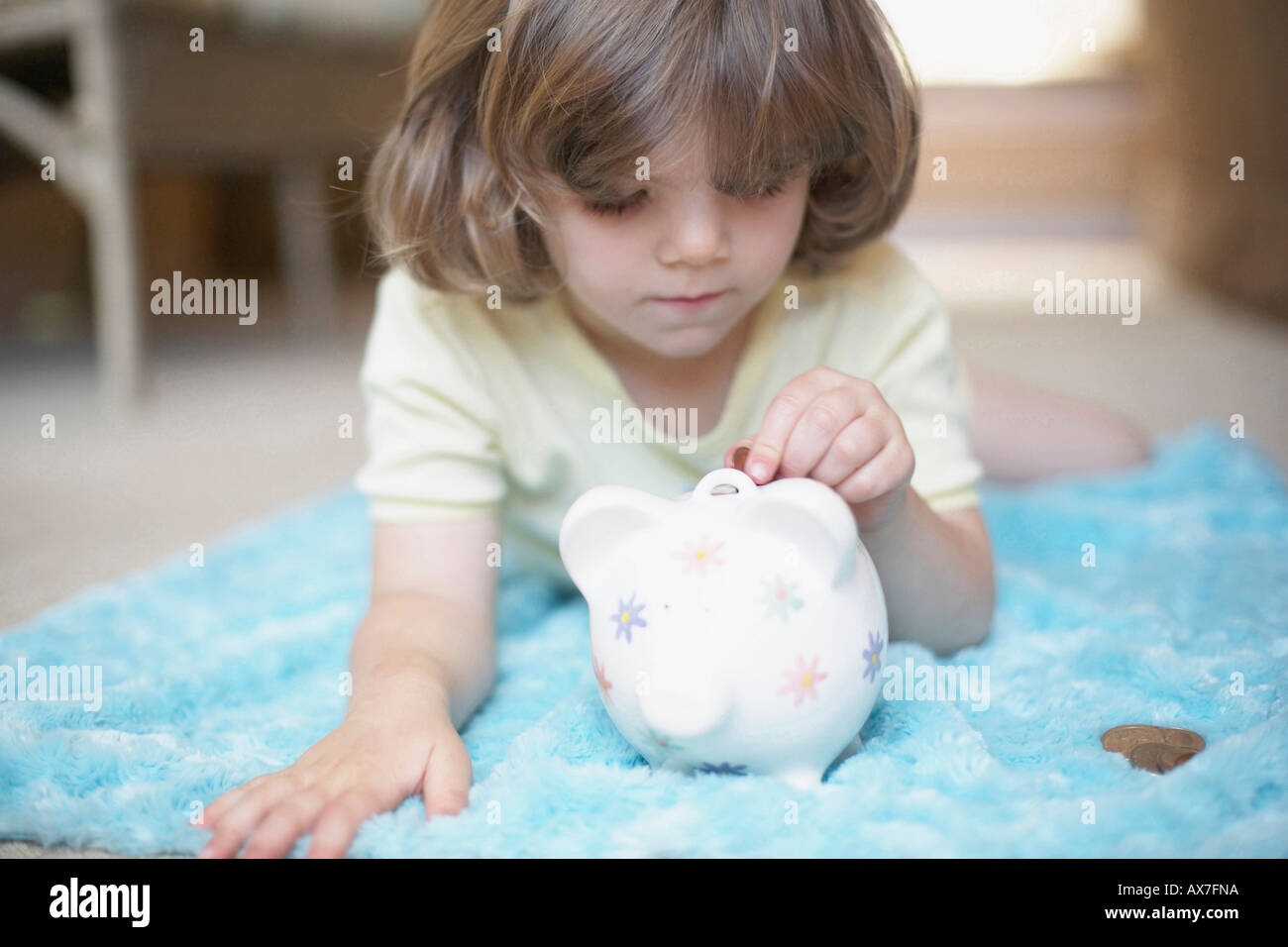 Close-up of a girl inserting a coin into a piggy bank Stock Photo - Alamy