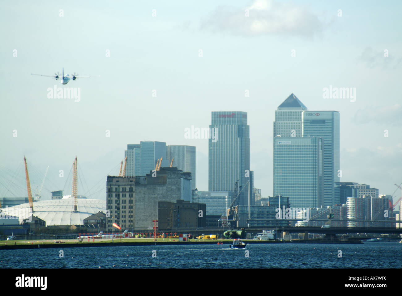 East London passenger plane taking off from City Airport above old Royal Albert Dock waters Dome & Canary Wharf skyline East London England UK Stock Photo