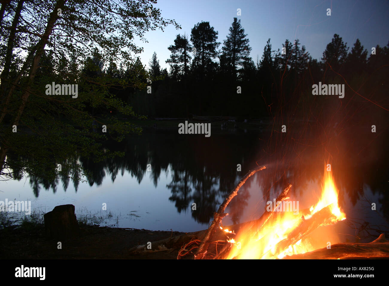 A peaceful campfire lights the night at this calm Oregon pond Stock Photo