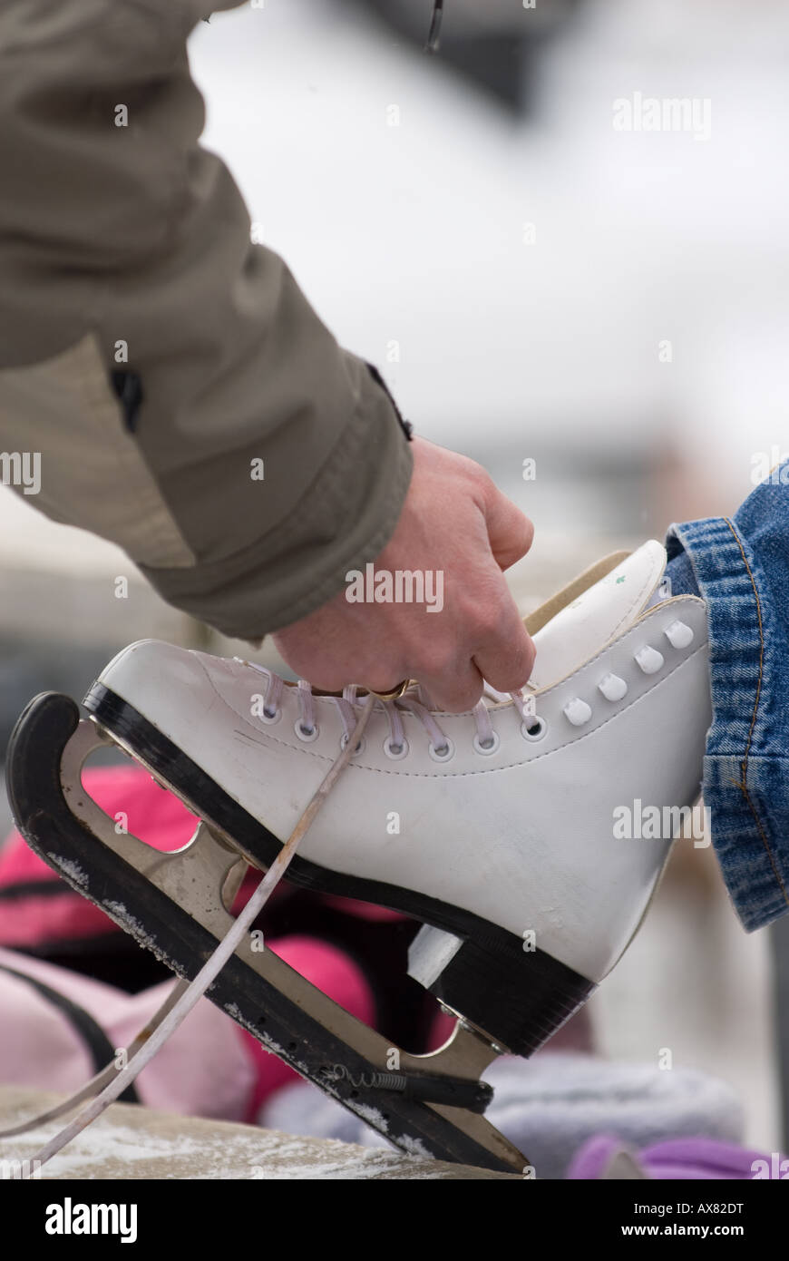 A father helps his young girl tie on ice skates during Kingstons Ontarios annual FebFest winter activities Stock Photo