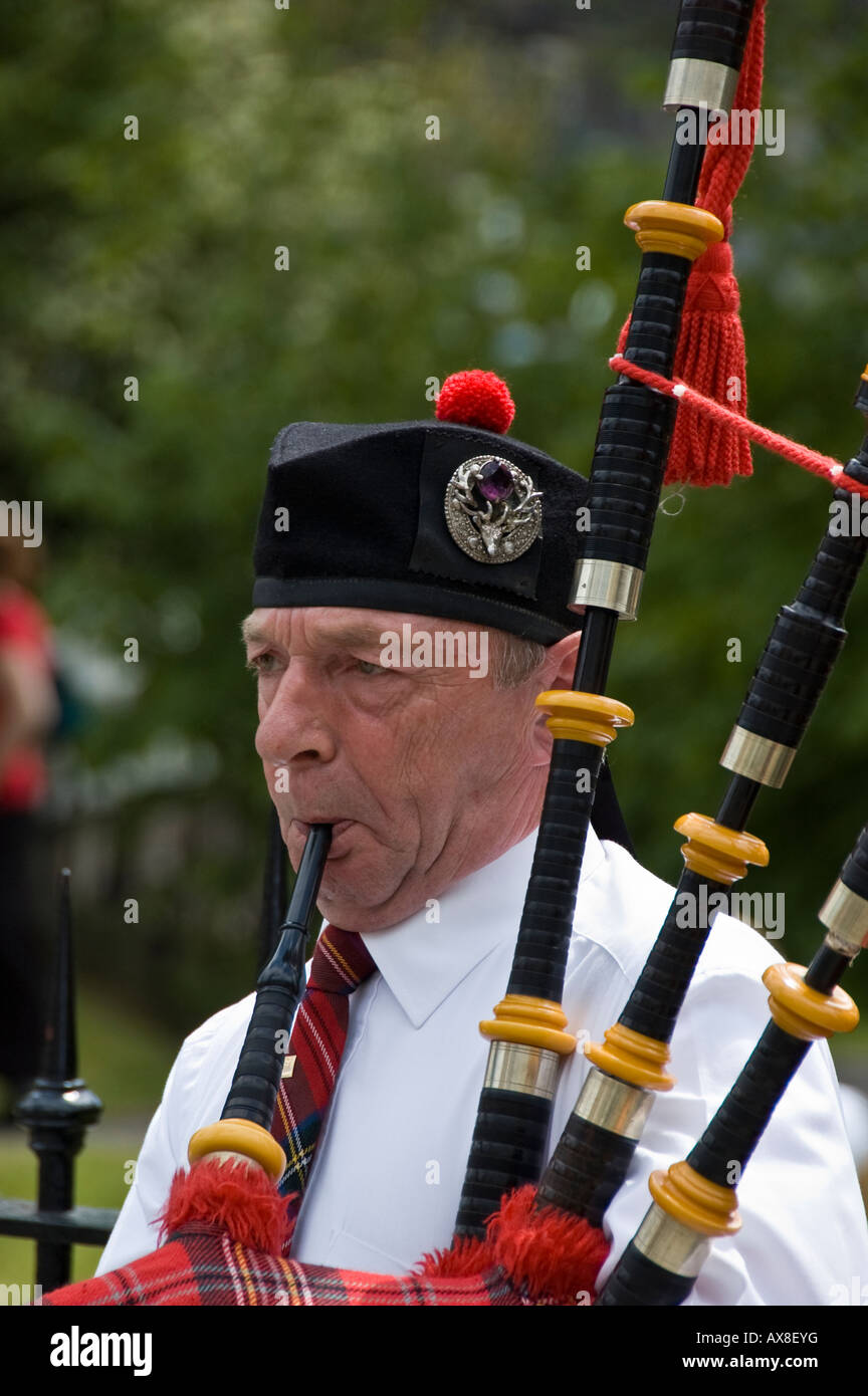 Man playing the bagpipes (busking) on Princes Street, Edinburgh Stock Photo