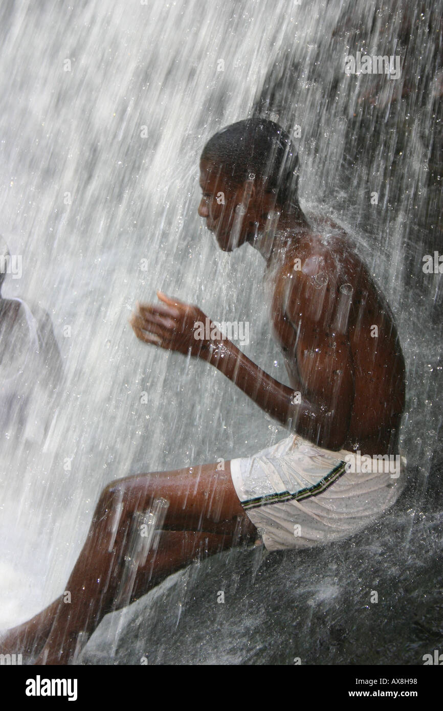 A young man taking a shower at the waterfalls at Kintampo in the