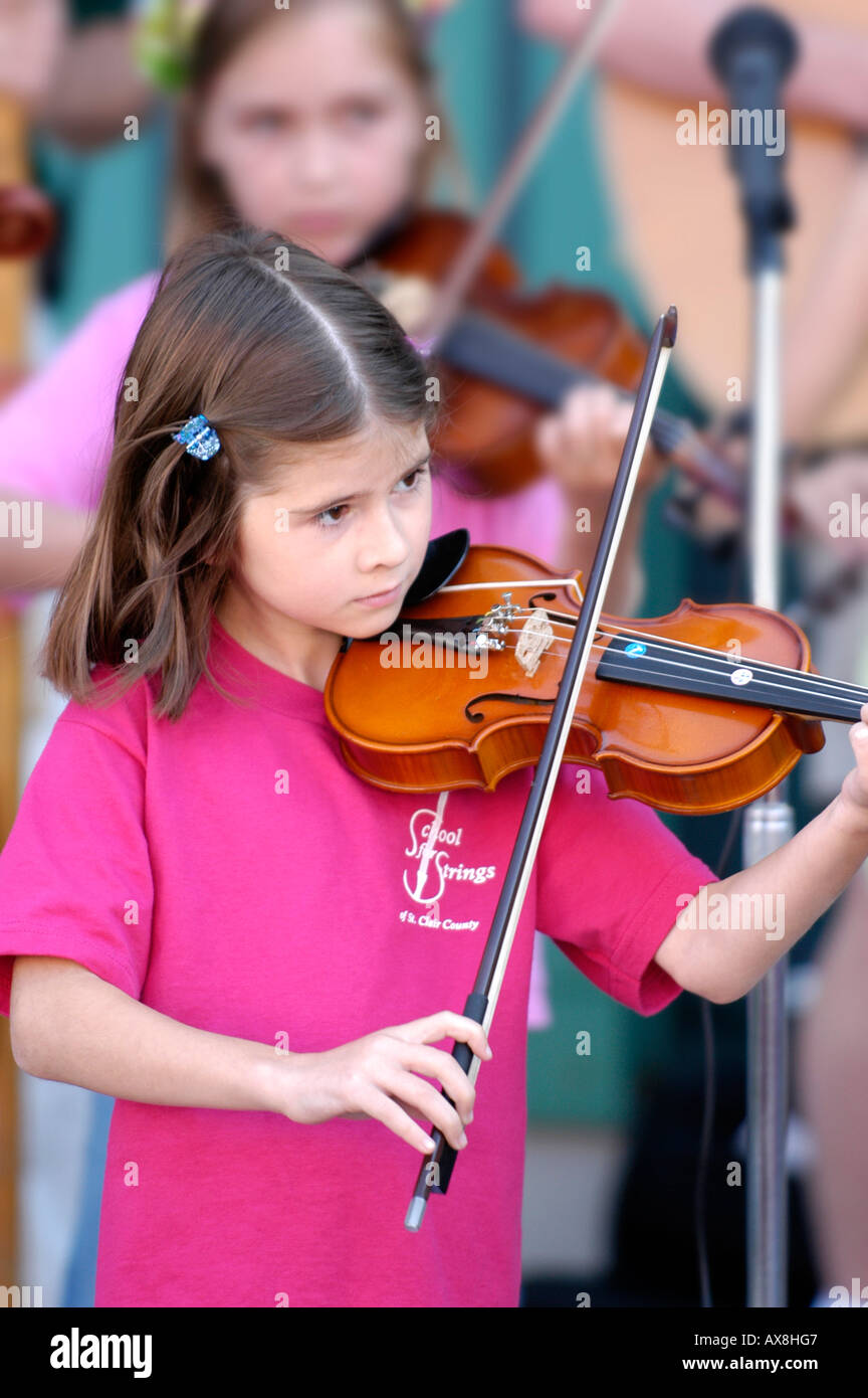 Violin strings group made up of children play a recital outside for the