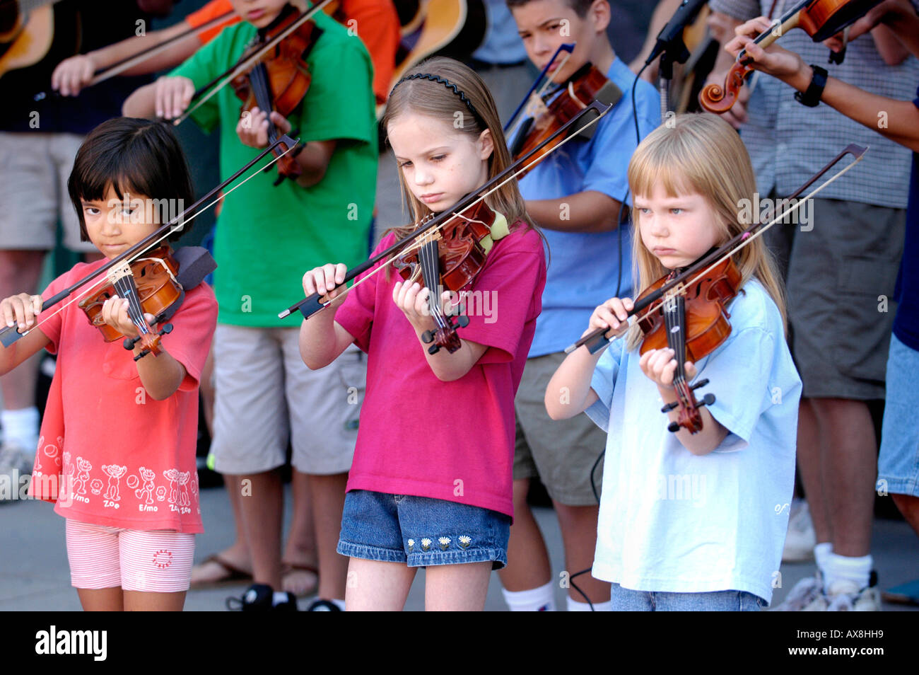 Violin strings group made up of children play a recital outside for the