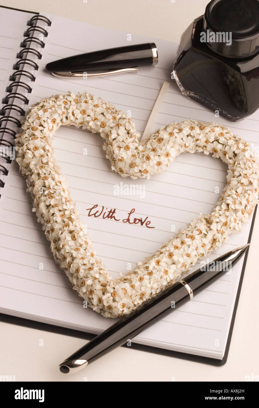 The words "with love" hand written by an ink fountain pen within a heart shape made of flowers Stock Photo