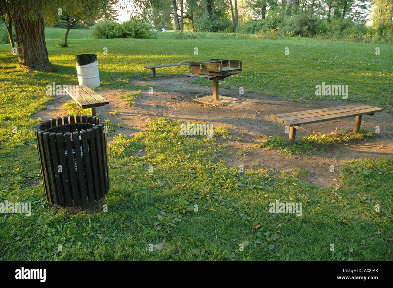 A Public Fire Pit Surrounded By Benches And Garbage Cans Stock