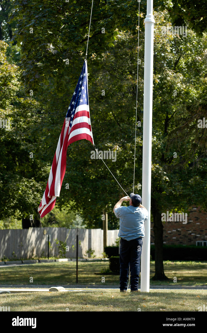 Lowering the flag at the end of the day being careful not to let it touch the ground Stock Photo