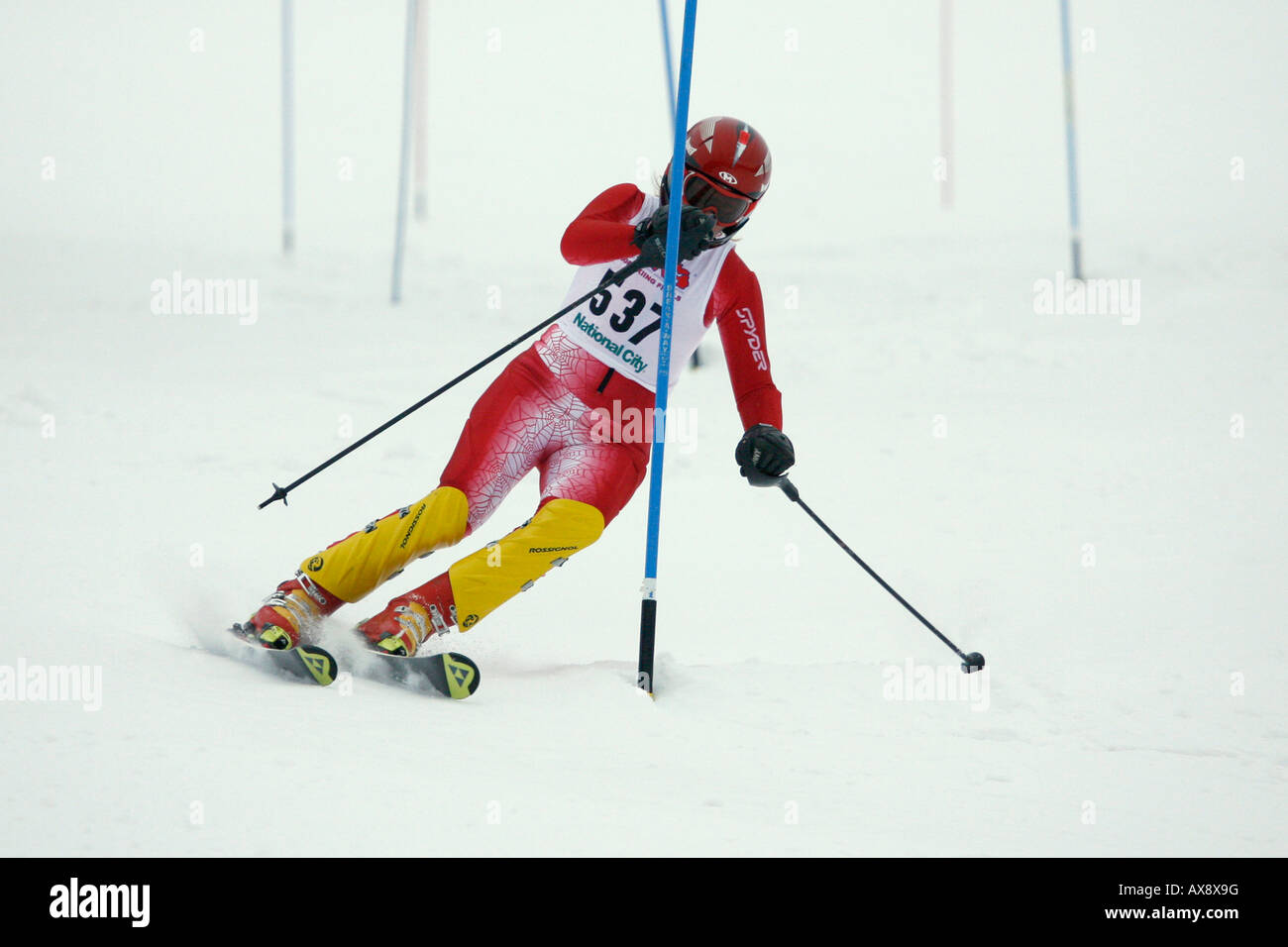 A skier turning at a gate in a downhill slalom race Stock Photo