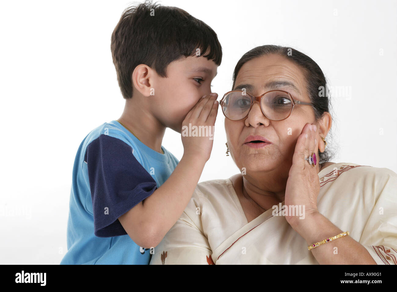 Boy whispering in the ears of his grandmother Stock Photo