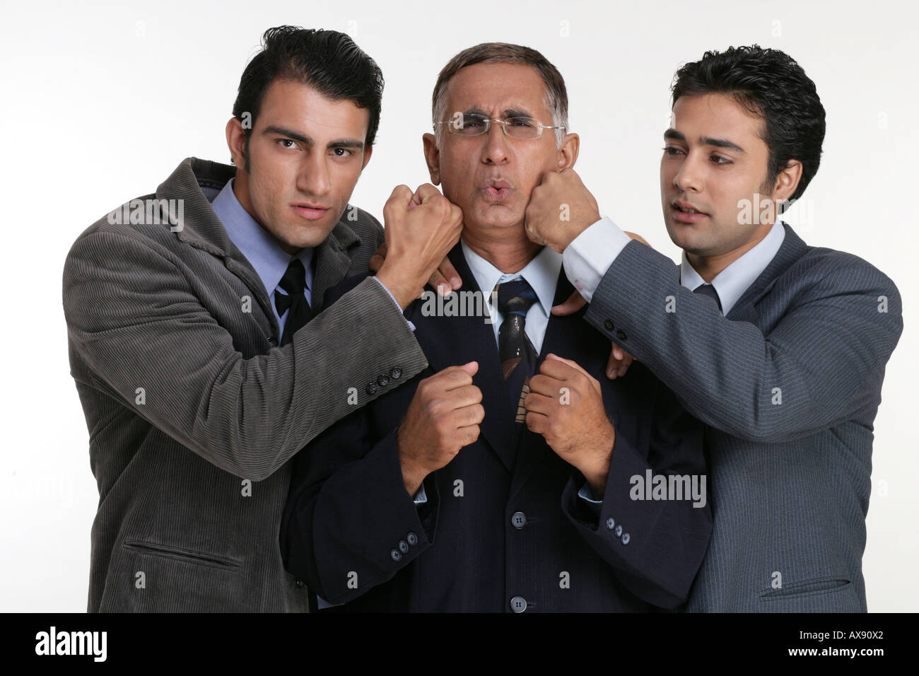 Portrait of two businessmen punching their colleague Stock Photo