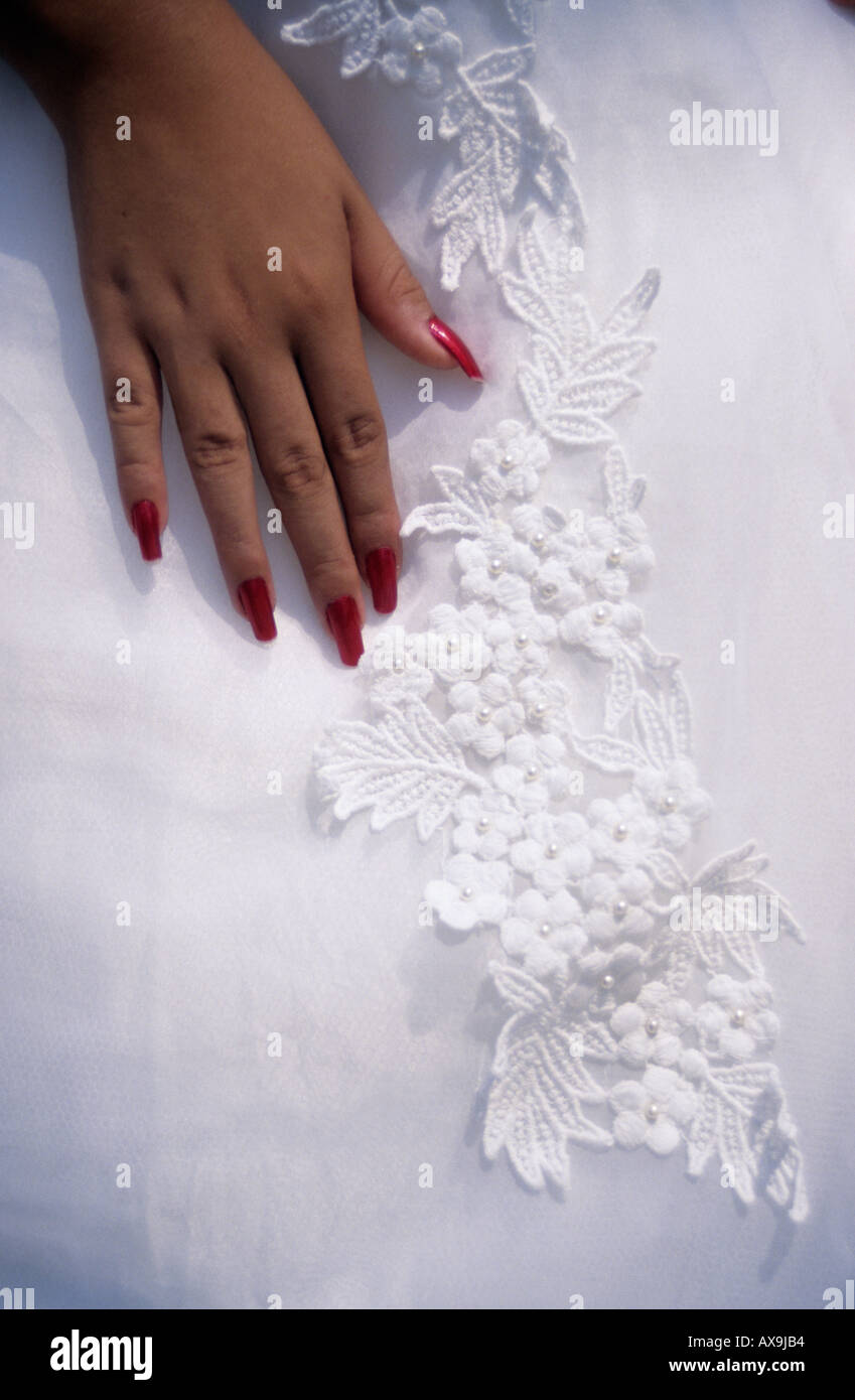 Hand with red fingernails on white embroidered dress Stock Photo