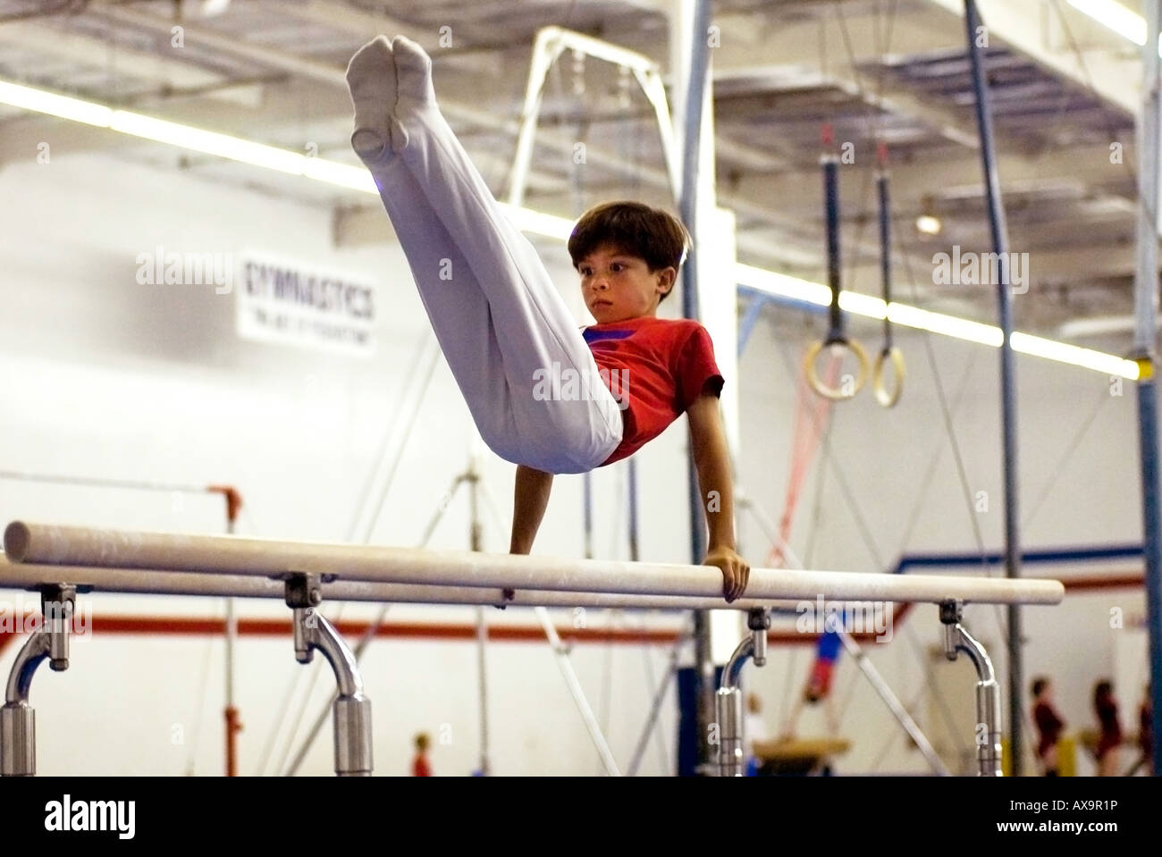 Boy performs on gymnastics parallel bar during demonstration meet at U