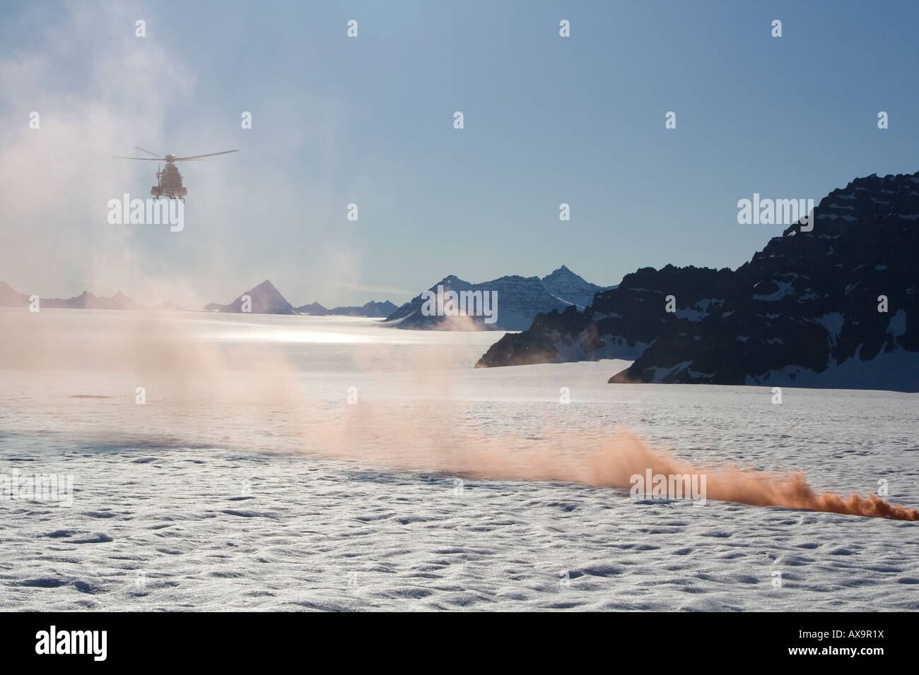 search and rescue coastguard helicopter landing on a glacier in Greenland with red distress flare Stock Photo