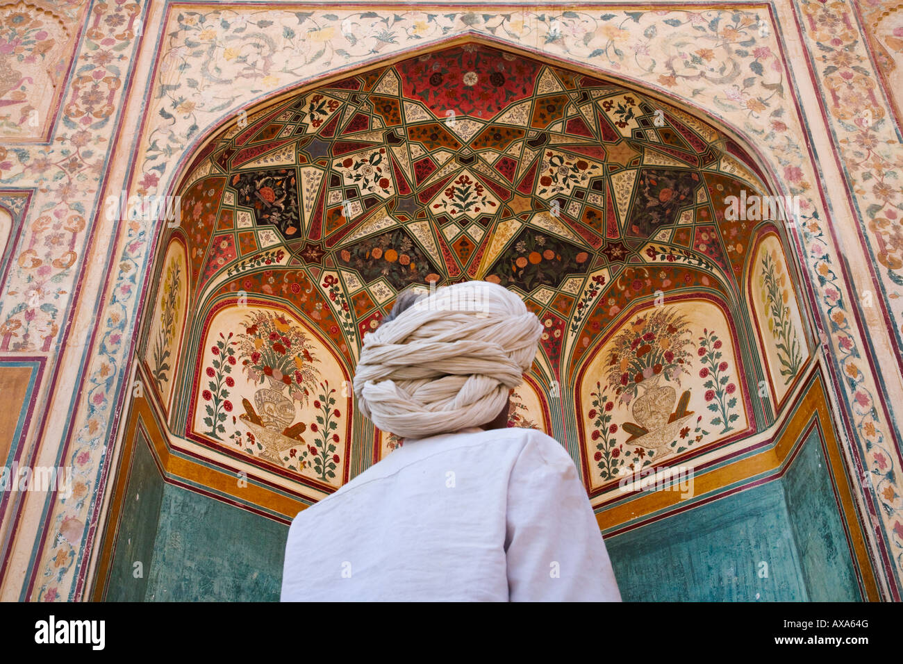 Man with ornate arcade decorated with tileworks inside Amber Palace Jaipur Rajasthan India Stock Photo