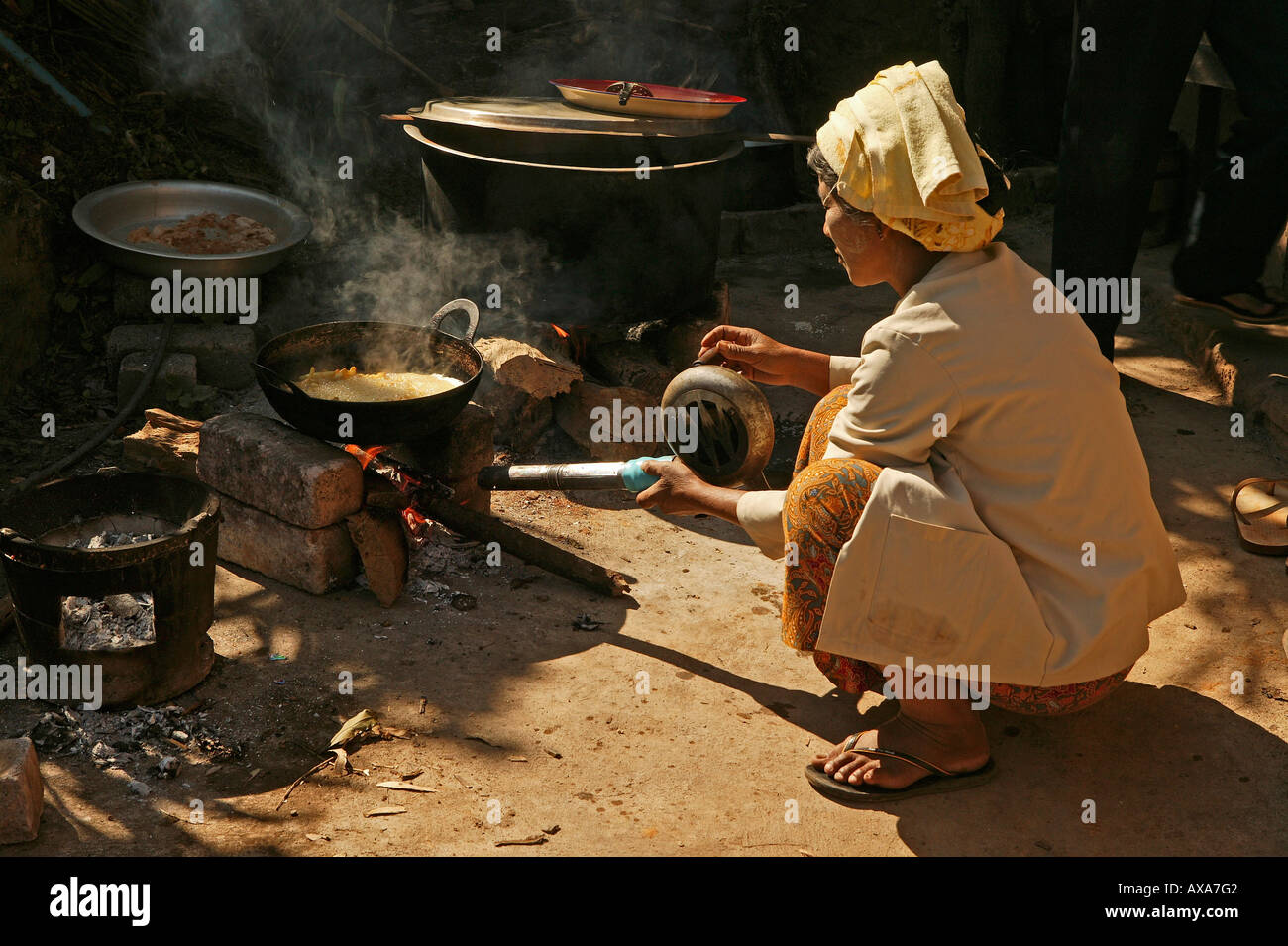 women crouching cooking outside, Myanmar Stock Photo