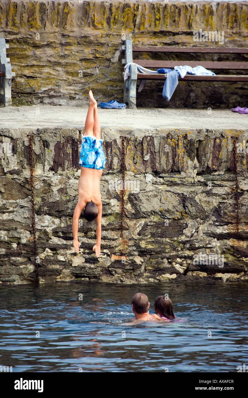 A boy dives in to the harbour at Polperro, Cornwall Stock Photo