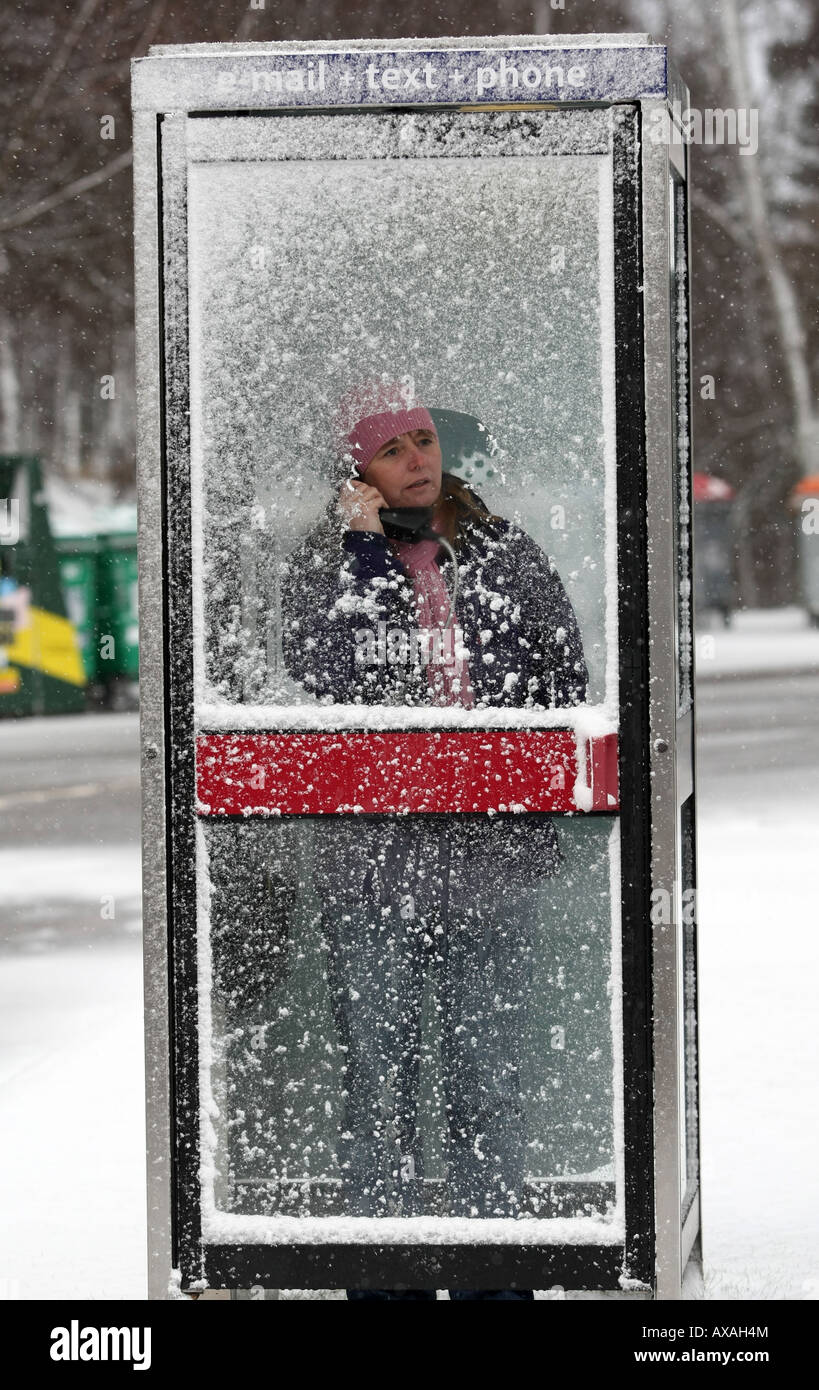 Woman making a call in a snow covered phone box in Braemar, Aberdeenshire, Scotland, UK Stock Photo