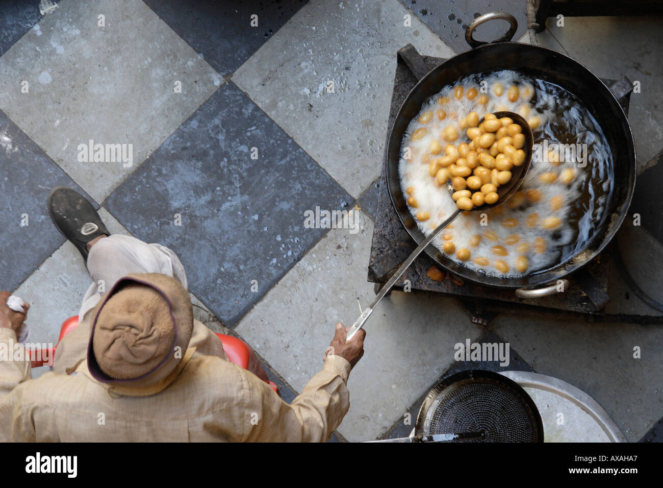 AAD73247 Man making Indian sweet food Gulab Jamun frying in oil Stock