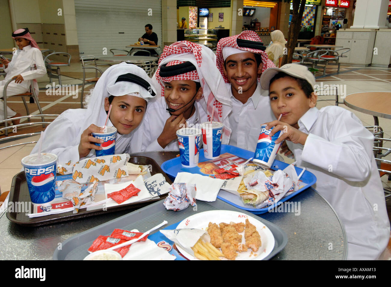 Qatari children in traditional outfits eating fast food in a Doha Stock