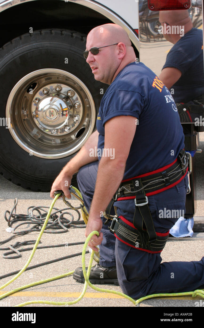 Fire Fighter knelling in front of truck holding onto the ropes from an ...
