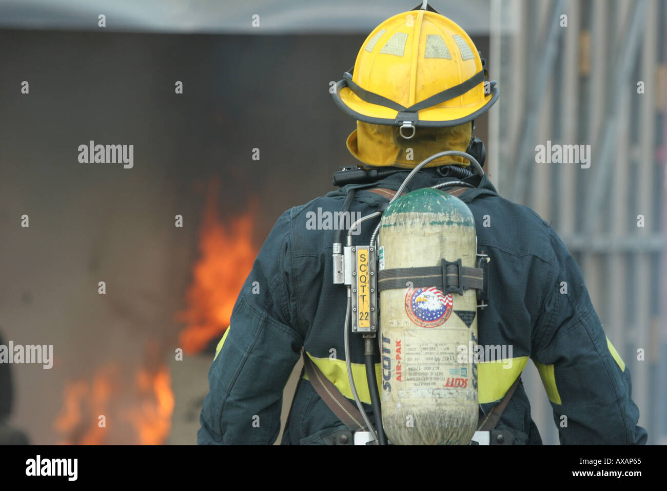Fire fighter in yellow hat investigating flames in a container Stock Photo
