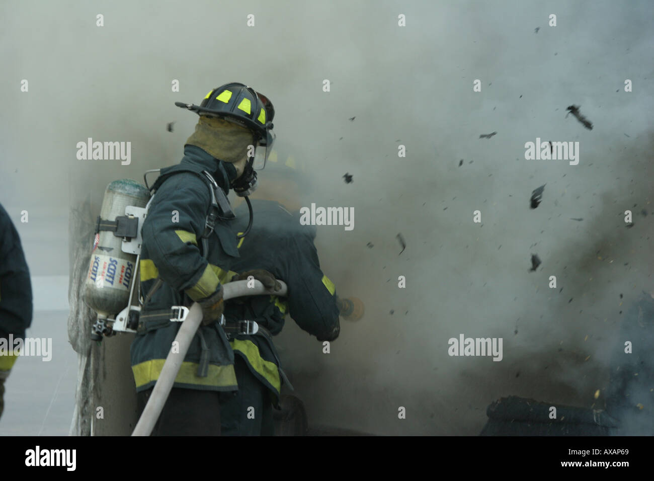 Fire fighters putting out fire in container with debris flying Stock Photo