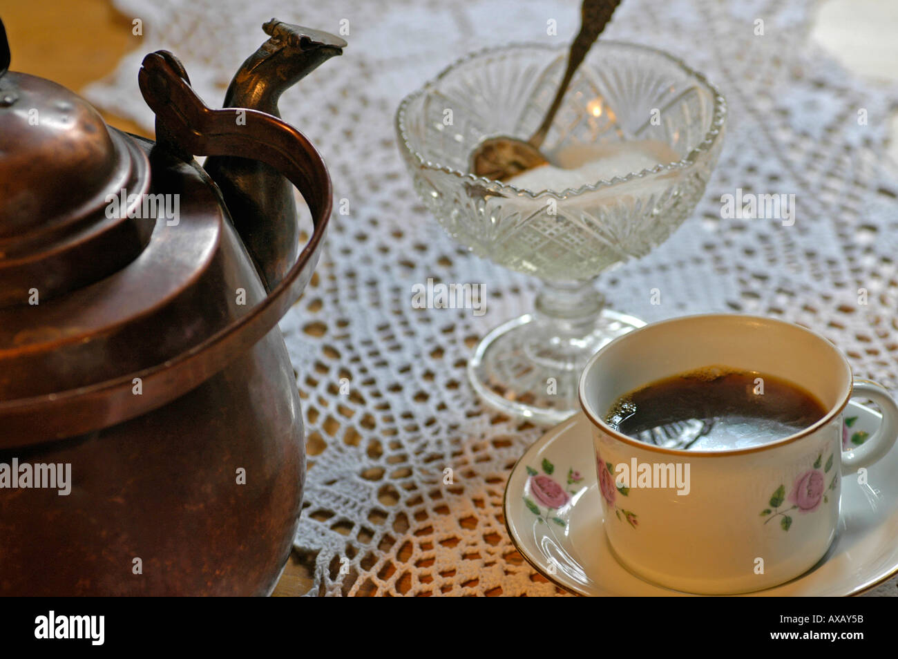 PR old copper coffee pot with a cup of coffee with sugar in an old sugar bowl with a suger spoon on crocheted table clothe Stock Photo