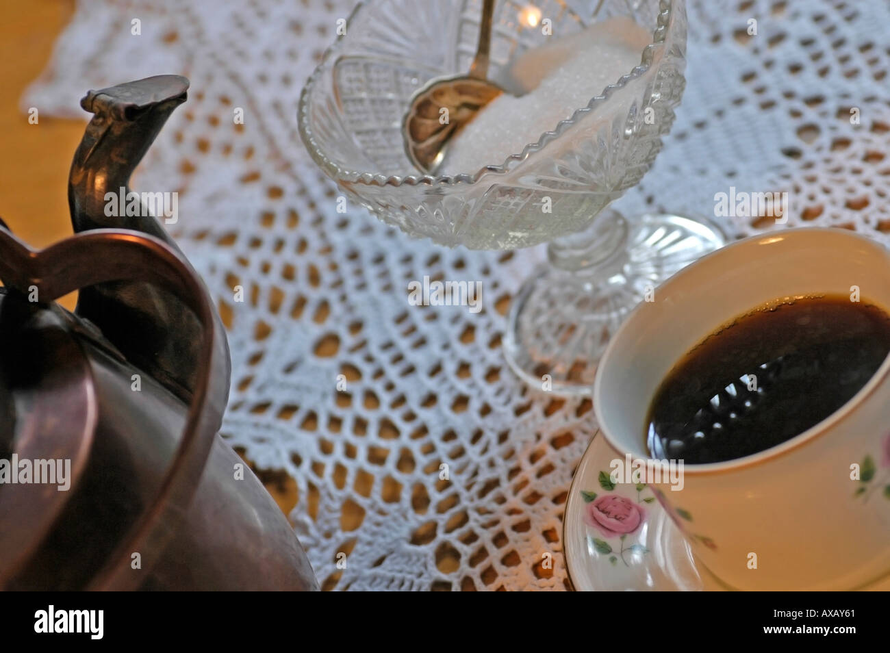 PR old copper coffee pot with a cup of coffee with sugar in an old sugar bowl with a suger spoon on crocheted table clothe Stock Photo