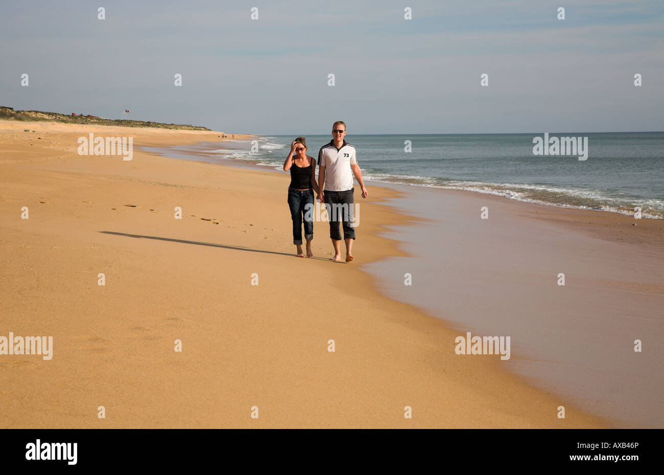 Young couple strolling together along a sandy beach. Stock Photo