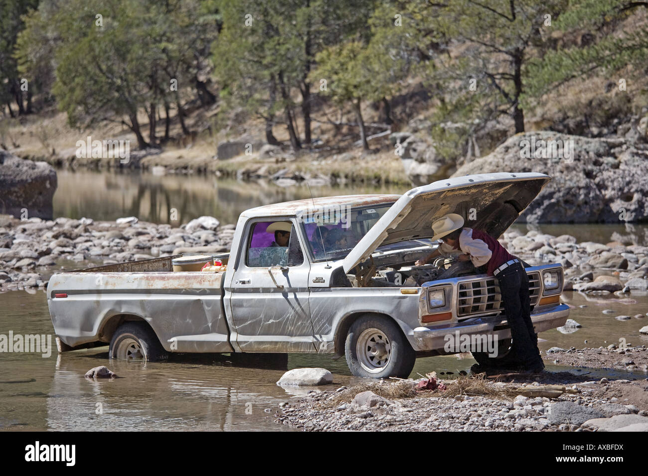Carichi Mexico Man fixing his car engine in a middle of a river near Carichi Chihuahua State Stock Photo