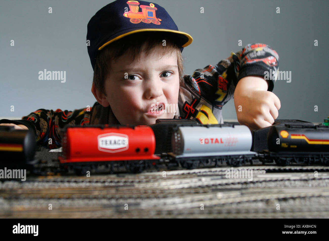 Lewis aged six and his Hornby electric train set. 00 H0 rolling stock track, Model train set with track, hat and whistle form part of the game. Stock Photo