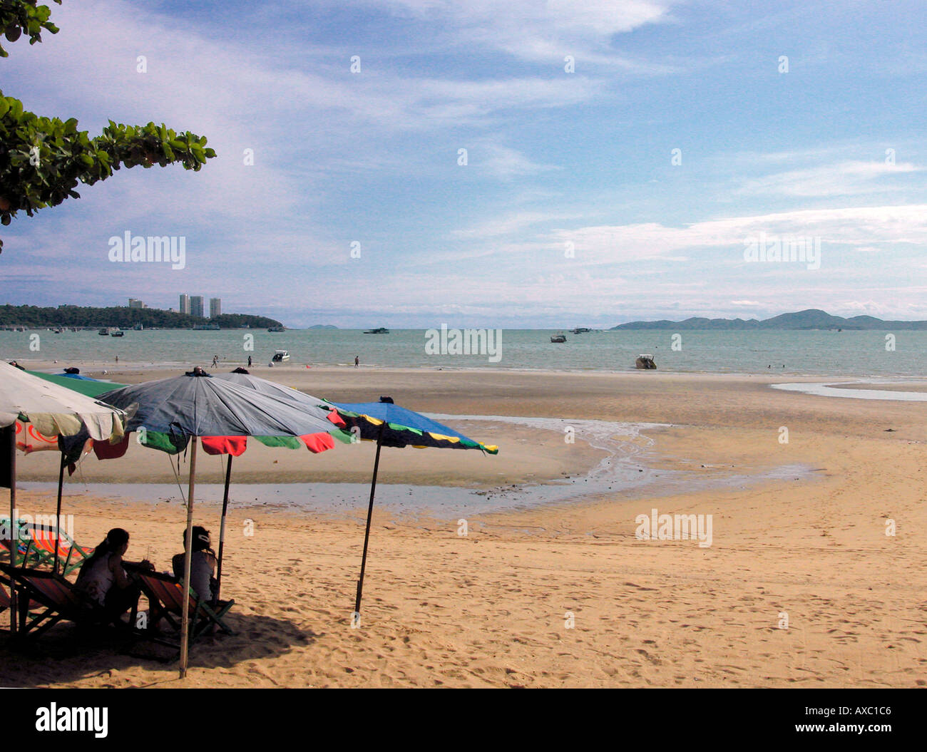 Pattaya Beach with sand and two women seated in deckchairs under umbrellas, Thailand Stock Photo